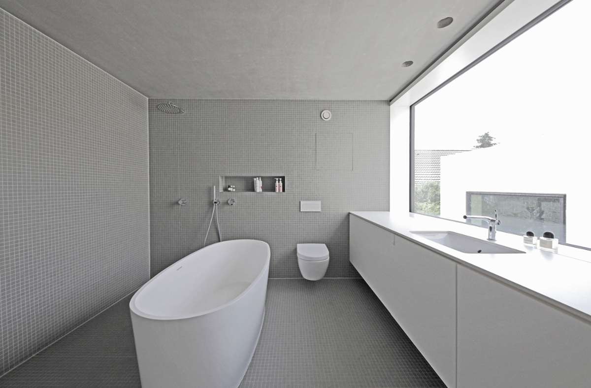 Minimalismus auch im Bad mit Badewanne, bodengleicher Dusche und grauen Mosaikfliesen.