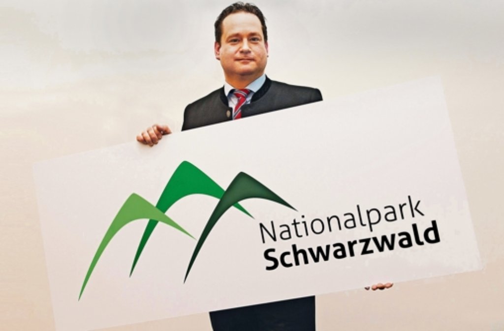Umweltfreundlich und naturnah – für einen nachhaltigen Tourismus steht auch der neue Nationalpark Schwarzwald. Minister Alexander Bonde (Grüne) stellt das Logo auf der CMT vor. Foto: dpa   Montage: Knauf