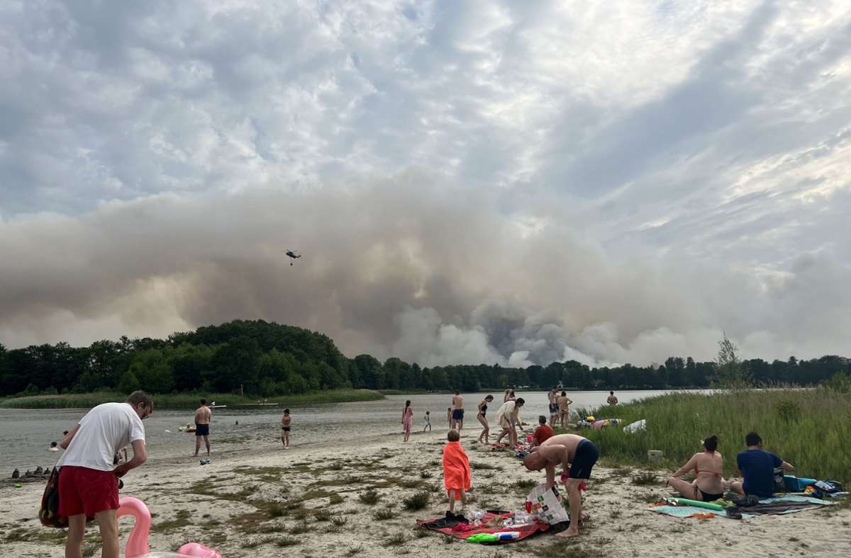 Brandenburg, Seddin: Ausflügler verbringen den heißen Tag am Seddiner See in dem ein Löschhubschrauber wegen des Waldbrandes bei Treuenbrietzen Wasser getankt hat.