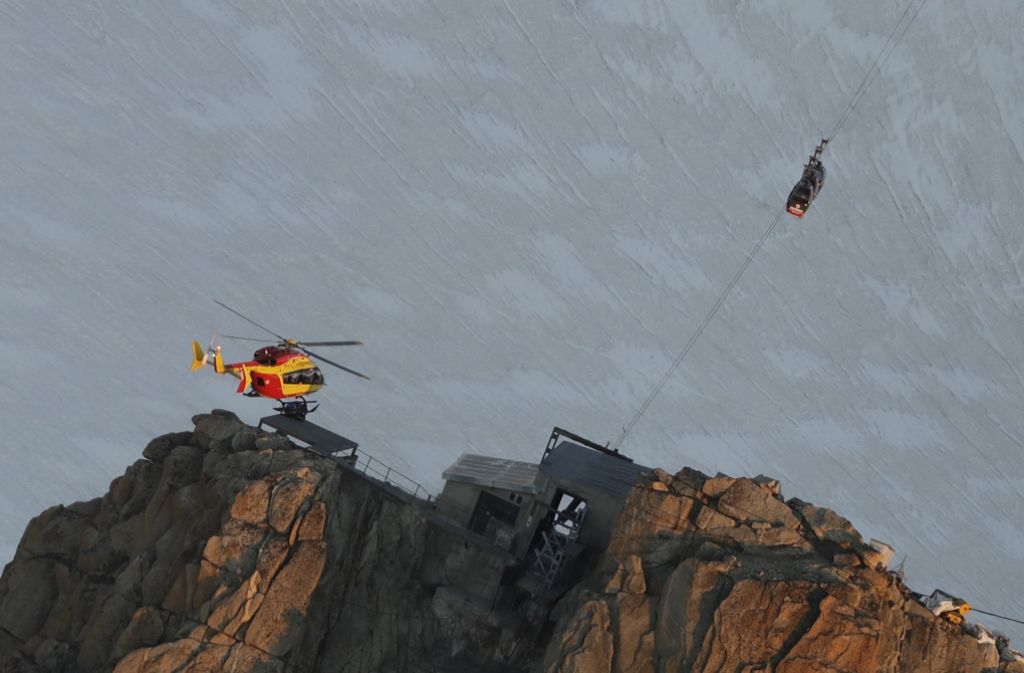 Ein französischer EC-135 Helikopter nahe den Gondeln, die unweit der Gipfelstation festhängen.