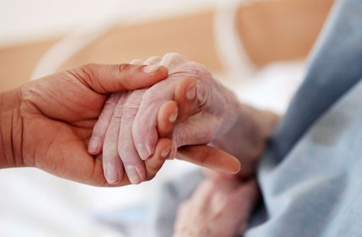 Eine Pflegerin hält in einem Altenheim die Hand einer Bewohnerin (Symbolbild). Foto: Oliver Berg/dpa