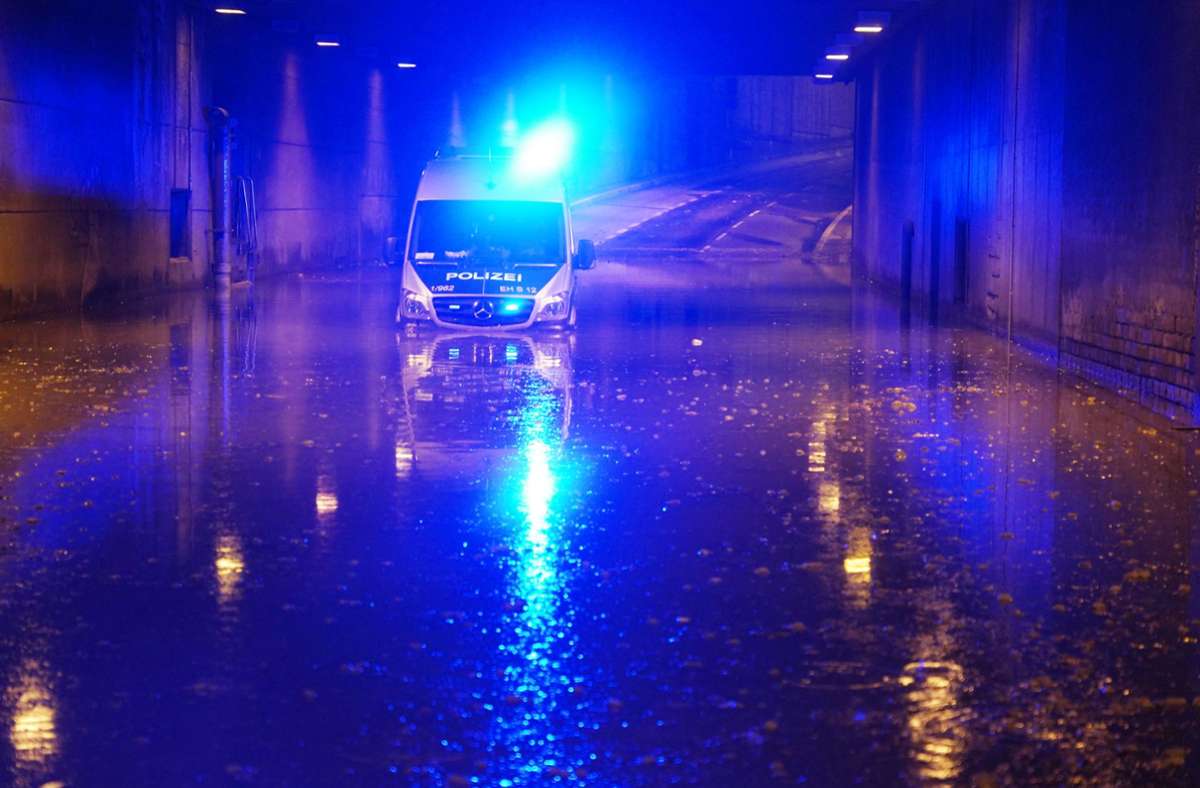 Juni 2021, Stuttgart: Ein Polizeifahrzeug blinkt noch mit Blaulicht, nachdem es in einer überschwemmten Unterführung liegen geblieben ist. Ein starkes Unwetter ist über weite Teile Baden-Württembergs hinweggezogen und hat dabei große Schäden angerichtet.