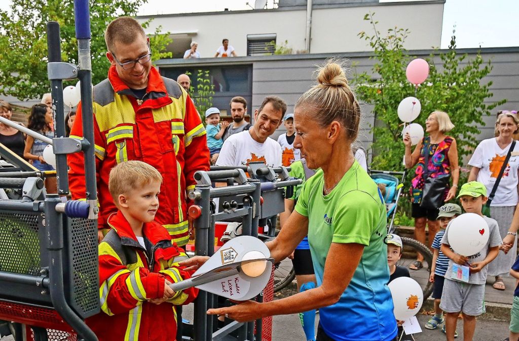 Der fünfjährige Emil Lieckfeldt übergibt die Angel-Fackel an die Laufleiterin Helga Grau-Ritter.