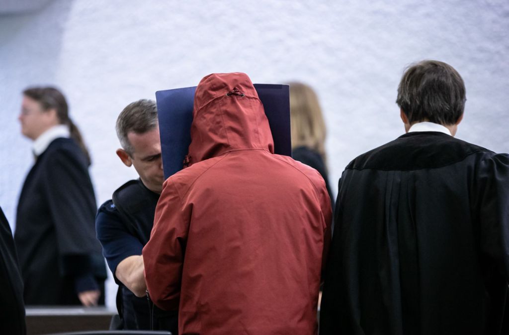 Der Angeklagte schützt sich beim Betreten des Saals vor den Blicken der Zuschauer. Foto: Lichtgut/Julian Rettig