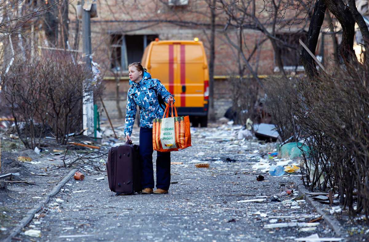 Ein Frau verlässt mit ihren Habseligkeiten ihre Wohnung in Kiew.