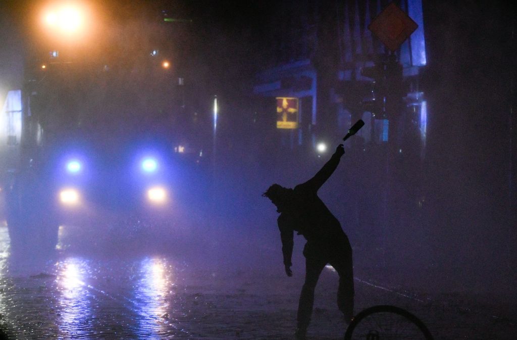 Ein Demonstrant wirft in der Nacht auf Sonntag in Hamburg im Schanzenviertel einen Flasche gegen einen Wasserwerfer.