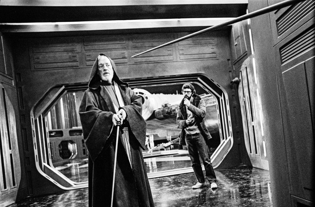 Alec Guiness als Obi-Wan Kenobi am Set von „Star Wars“ (1977), im Hintergrund der Schöpfer und Regisseur George Lucas. Guiness sträubte sich dagegen, dass seine Figur im Kampf gegen Darth Vader sterben sollte, aber Lucas konnte ihn schließlich überzeugen.