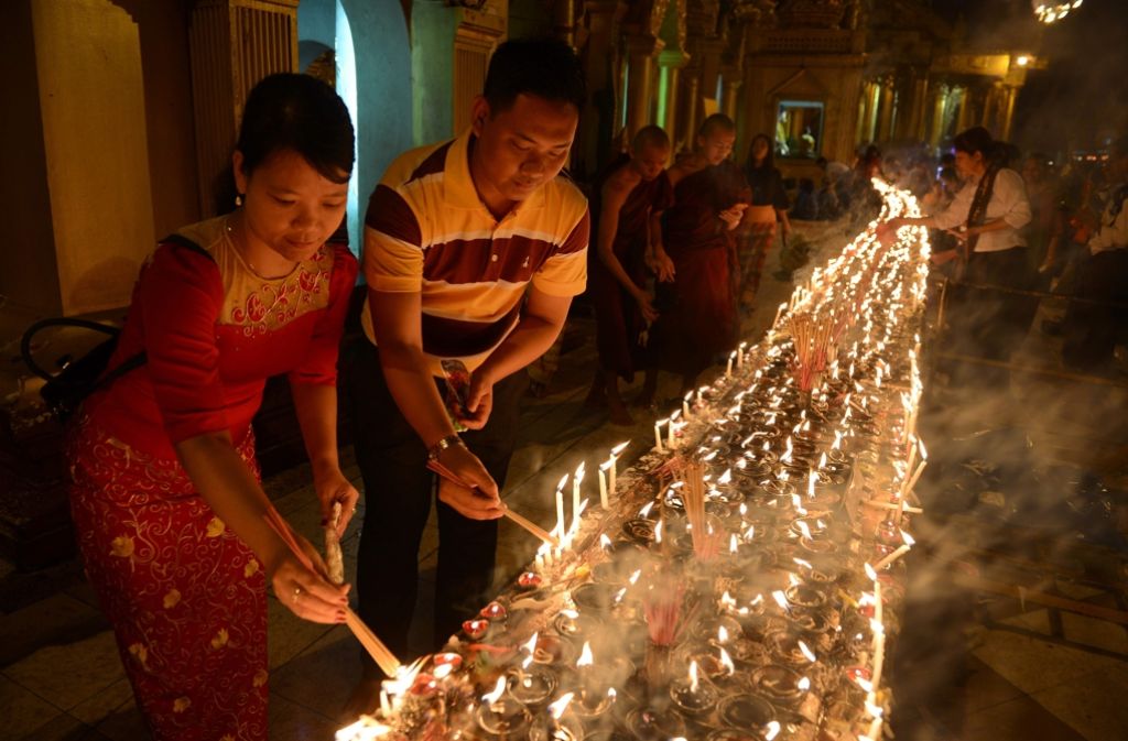 Gläubige und Mönche entzünden gemeinsam Kerzen.