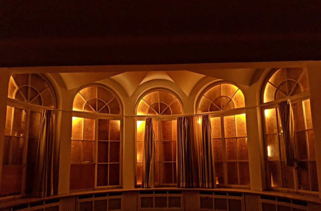 Das Terrassenzimmer in dem Rundbau an der Villa Berg. Licht fällt nur durch die Ritzen der Holzabdeckungen auf den Fenstern nach drinnen.