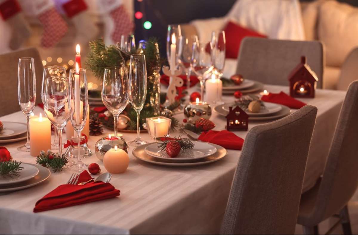 Ein weihnachtliches Tischgesteck, viele Kerzen und schöne Deko auf den Tellern.