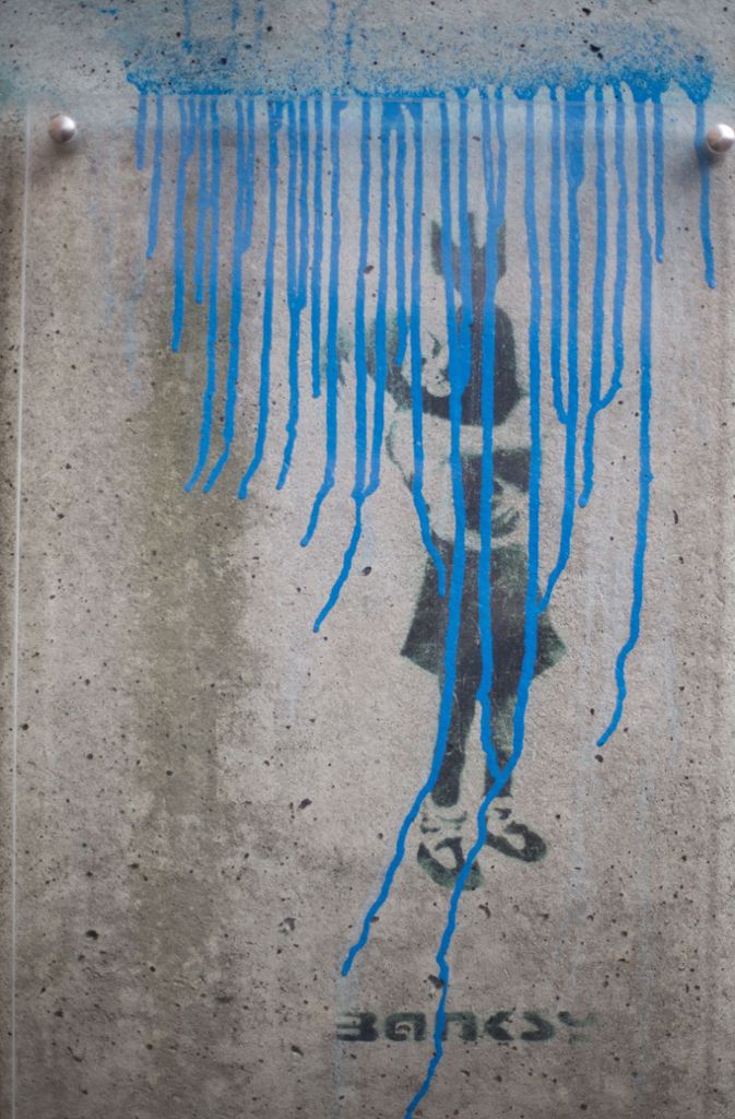 Anschlag In Hamburg wurde Banksys Schablonengraffito „Bomb Hugger“ von einem unbekannten Täter zerstört, der mit blauer Farbe das Wort „Grafitti“ und eine Linie oberhalb des Bildes gesprüht hatte.