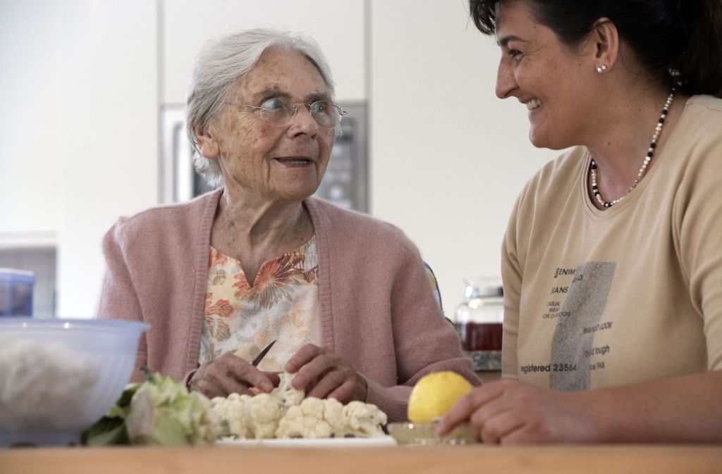 Zu zweit geht vieles besser: Eine Seniorin in einer Wohngemeinschaft für Pflegebedürftige lässt sich von einer Alltagsbegleiterin helfen.