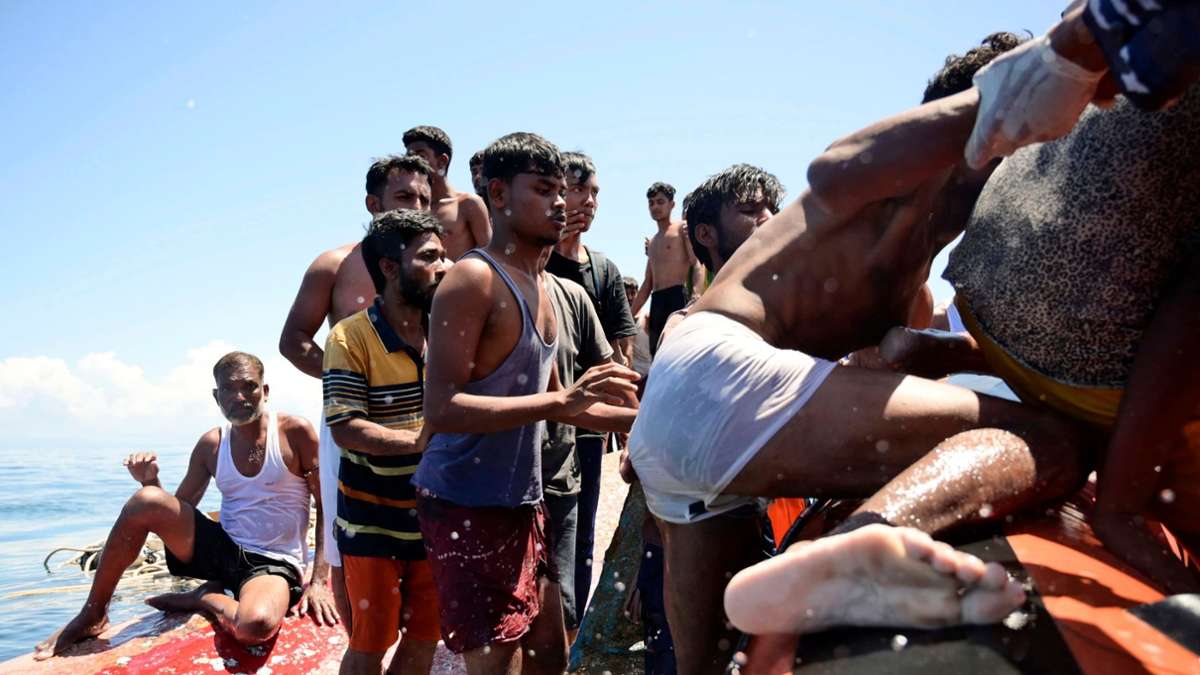 Rohingya-Flüchtlinge klettern auf ein Boot der Nationalen Such- und Rettungsagentur in Indonesien. Sie werden gerettet, nachdem ihr Boot in den Gewässern vor West-Aceh gekentert ist.