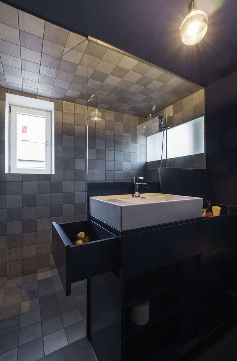 Blick ins Badezimmer mit bodengleicher Dusche und Waschbecken, die Möbel sind passgenau für den Raum entworfen worden.