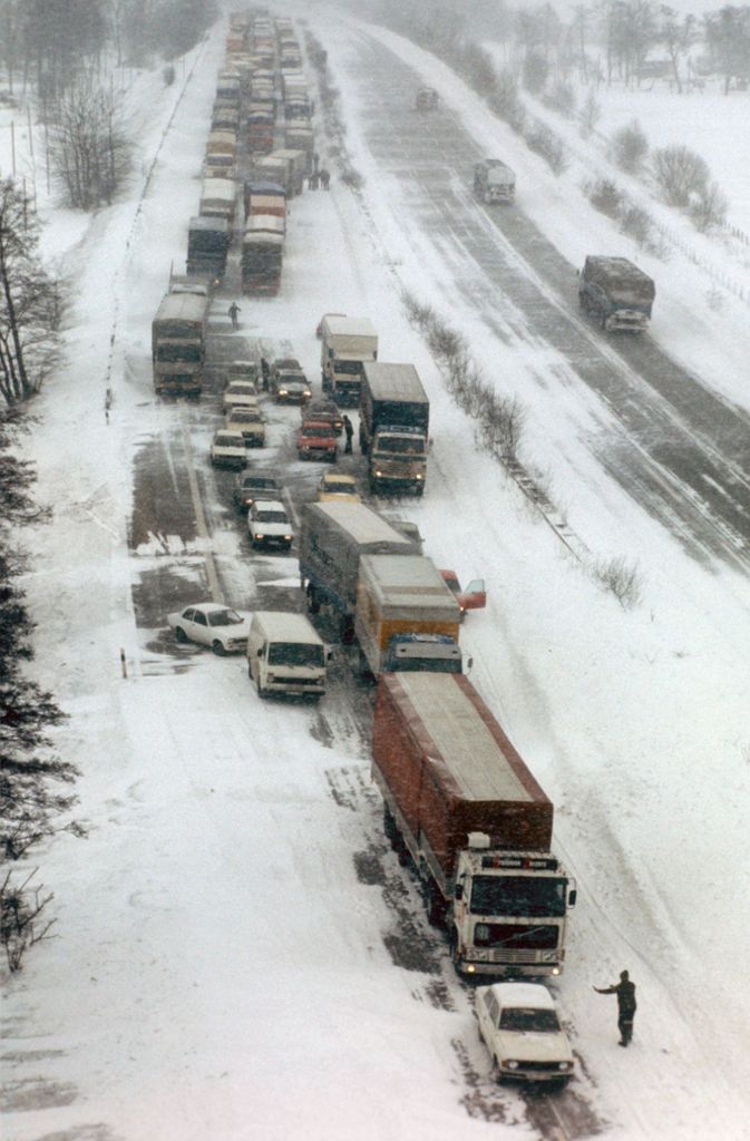 Im Schnee stecken gebliebene Lastwagen und PKW am Straßenrand der Autobahn bei Kiel.