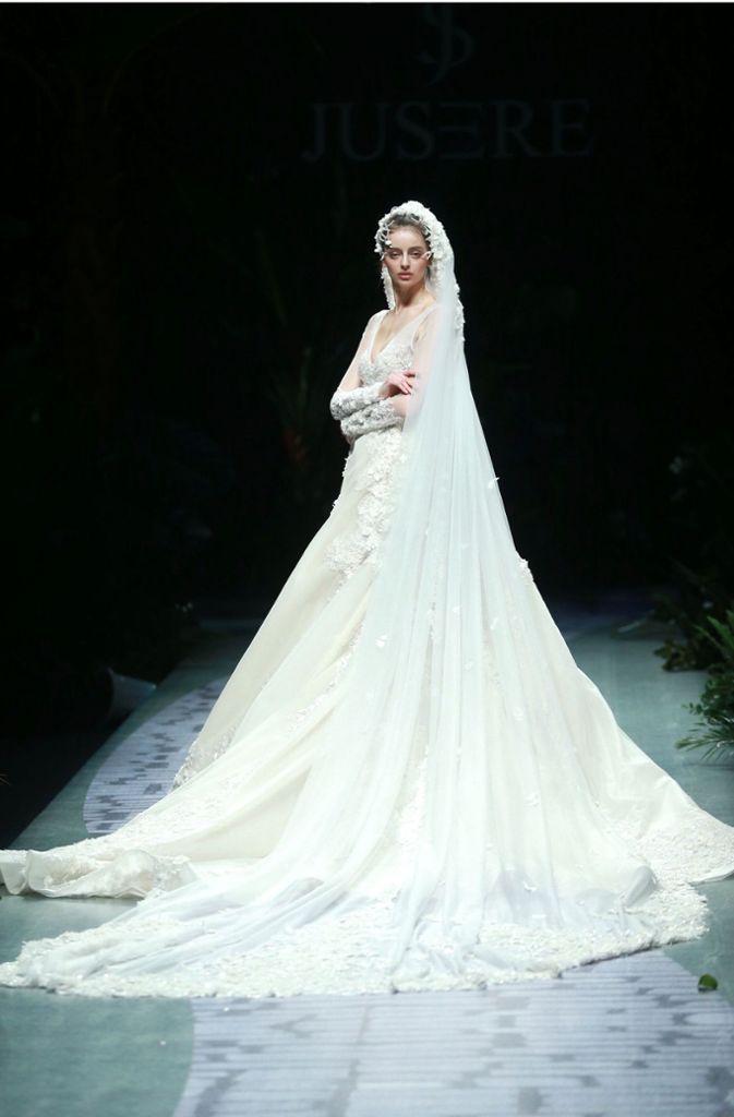 Wie in einem Märchen: Ein Model trägt während der Show des Designers Yu Aiping ein atemberaubendes Brautkleid mit aufwendigem Schleier, Stickereien und einer meterlangen Schleppe.