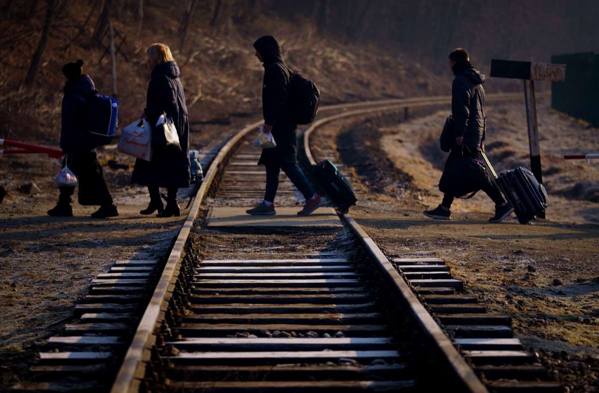 Eine Familie, die vor dem Krieg in der Ukraine geflohen ist, überquert mit ihrem Gepäck eine Eisenbahnlinie an der Grenze zu Polen in Kroscienko.