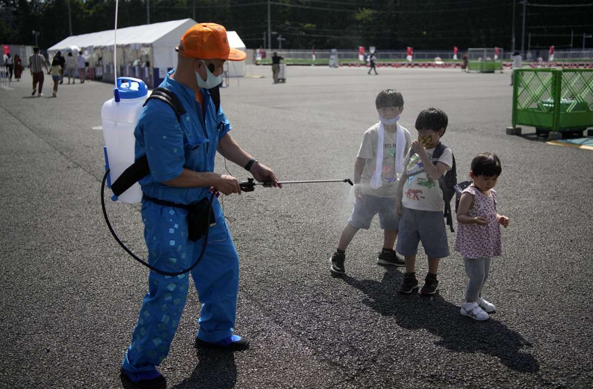 Abkühlung gefällig? Ein Olympia-Mitarbeiter besprüht Kinder zur Erfrischung mit Wasser.