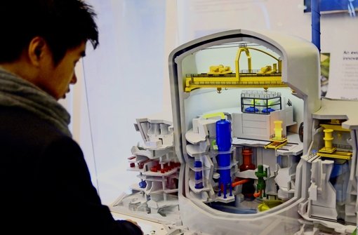 Ein Besucher der “Welt-Nuklear-Ausstellung“ in Paris betrachtet das Modell eines Atomkraftwerkes. Man könnte den Reaktor  auch dort kaufen. Foto: AFP