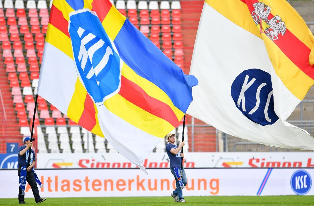 Vor der Partie schwenken Karlsruhe-Fans die Fahnen vor den leeren Rängen.