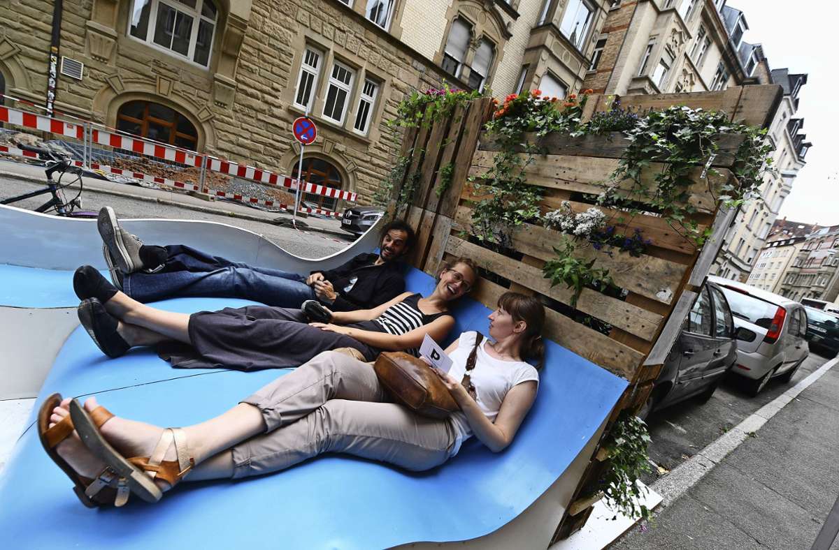 Junge Leute machen es sich im Sommer 2016 auf einem Parklet in Stuttgart bequem.|