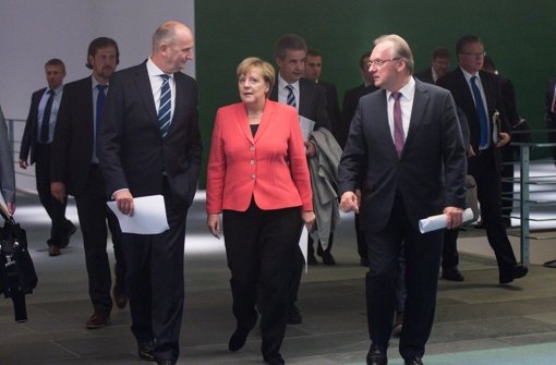 Kanzlerin Angela Merkel (Mitte, CDU), Brandenburgs Ministerpräsident Dietmar Woidke (links, SPD), und Reiner Haseloff (CDU), Regierungschef von Sachsen-Anhalt schreiten zur Pressekonferenz, um die Ergebnisse des Flüchtlingsgipfels zu verkünden. Foto: dpa