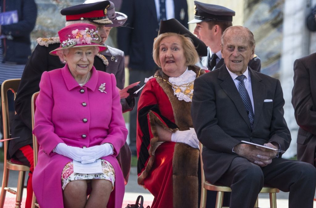 Die Queen, pretty in pink, und ihr Ehemann Philip bei der Eröffnung der Feierlichkeiten anlässlich des 90. Geburtstags der Monarchie. Großes Staunen bei der Dame im Hintergrund.
