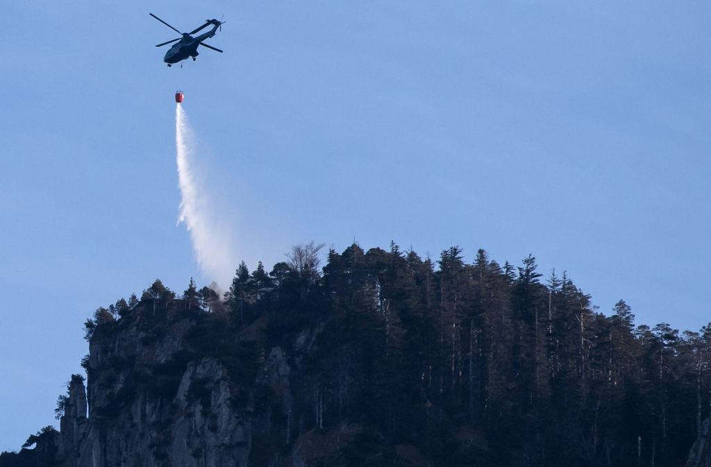 Ein Hubschrauber fliegt am 2. Januar in Kochel am See (Bayern) über dem Kochelsee. Ein Bergsteiger hatte am Jochberg einen Flächenbrand ausgelöst. Rund hundert Hektar Wald und Wiese standen in Flammen, die Löscharbeiten könnten nach Angaben des Landratsamtes noch Tage dauern.