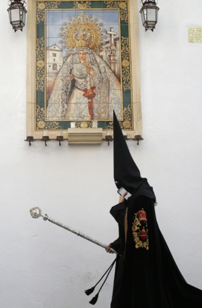 Tradition und Moderne vereint: Ein „Nazareno“ in Córdoba mit Smartphone.