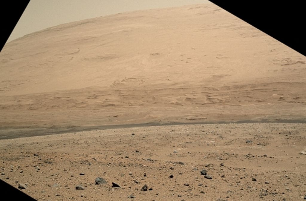 Curiosity fährt seit einigen Tagen auf den Berg Mount Sharp zu. Vor dem Berg sind Dünen zu erkennen. Das Bild stammt von der Kamera MAHLI, die eigentlich für Nahaufnahmen gedacht ist. Während der Fahrt liegt sie an der linken Seite des Roboters an und zeigt gewissermaßen den Blick, den ein Fahrer von Curiosity hätte.