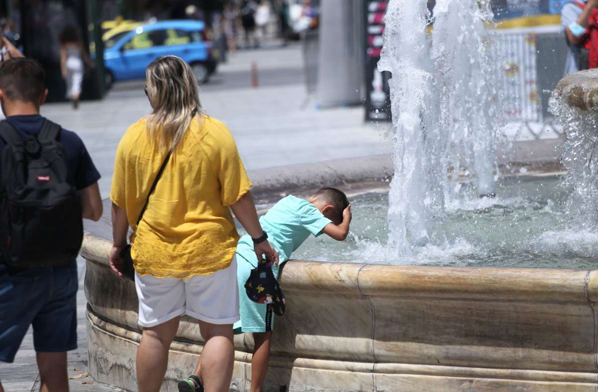 Ein kleiner Junge sucht an einem Brunnen in Athen Erfrischung .
