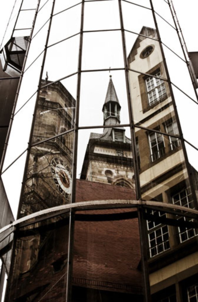 In einer Fassade vis-a-vis spiegeln sich die Türme von Stuttgarts ältestem und größtem Sakralbau, der Stiftskirche. Im Juli 2003 wurde das Gotteshaus nach vierjähriger Restaurierung feierlich wiedereröffnet. Der wuchtige Westturm (links im Bild) und der filigranere Südturm (Mitte) ragen hoch über die Dächer der Innenstadt hinaus. Zwar sind die Türme eines der Wahrzeichen Stuttgarts nicht jeder Zeit für Besucher geöffnet, doch am Samstag, dem 13. August von 11 bis 16 Uhr, bietet sich die seltene Gelegenheit, den Westturm zu ersteigen.Nur ganze sieben Mal kann man im Jahr 2016 den herrlichen Blick vom Westturm der Stiftskirche hinab auf den Schillerplatz und weit darüber hinaus genießen.