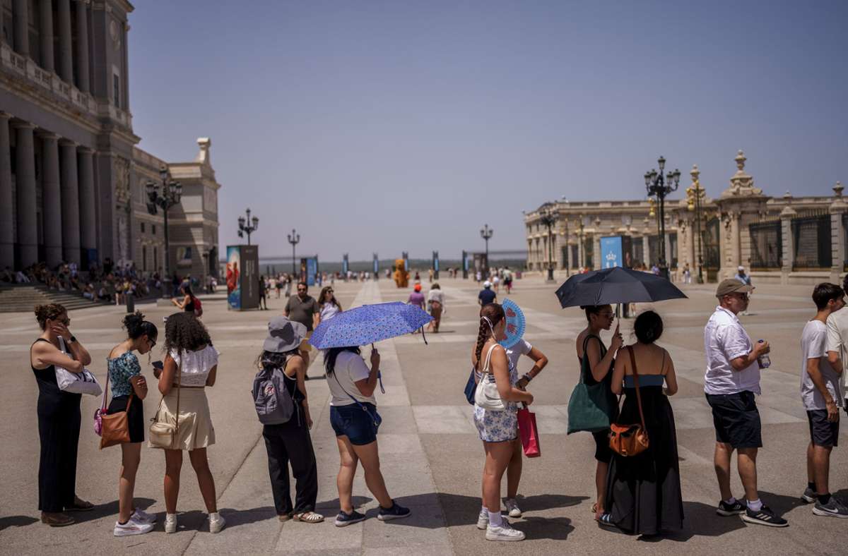 Menschen stehen an einem heißen und sonnigen Sommertag in Madrid Schlange, um den Königspalast zu betreten.