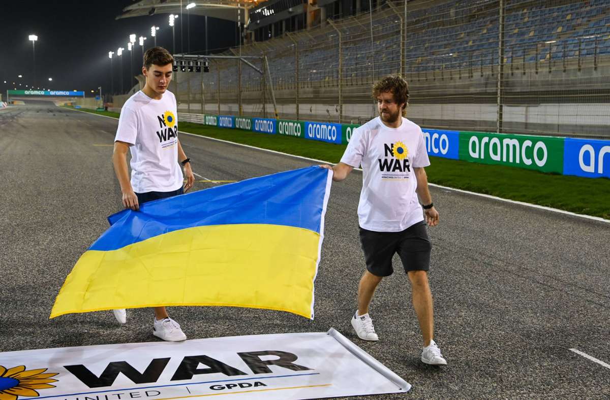 Sebastian Vettel (Aston Martin) (rechts) und George Russell (Mercedes-AMG) platzieren die Ukraine-Flagge.