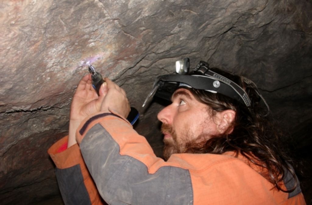Der Projektleiter Alistair Pike entfernt etwas Calcit von der Höhlenwand.