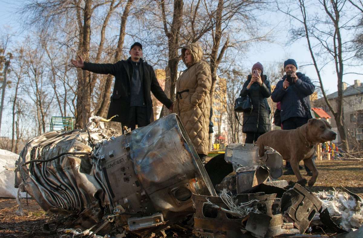 Anwohner stehen in Charkiw um die Fragmente eines Geschosses herum.
