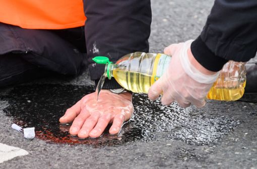 Mit viel Öl kann die Polizei festgeklebte Hände vom Asphalt lösen. Foto: dpa/Julian Stratenschulte