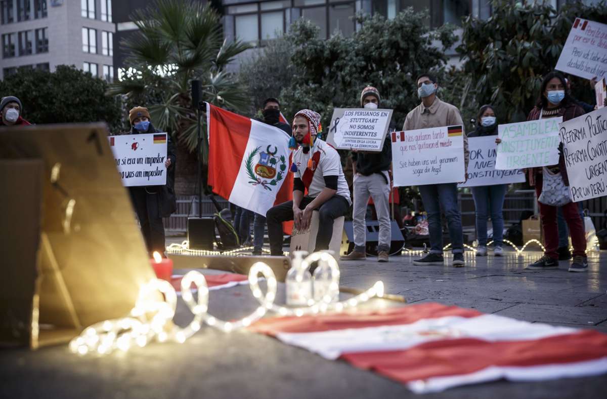 Rote und weiße Kerzen brennen auf dem Sockel der Spiegelskulptur vor den Portraits der beiden Männer, die vor einer Woche bei Demonstrationen in Peru durch Polizeigewalt starben.