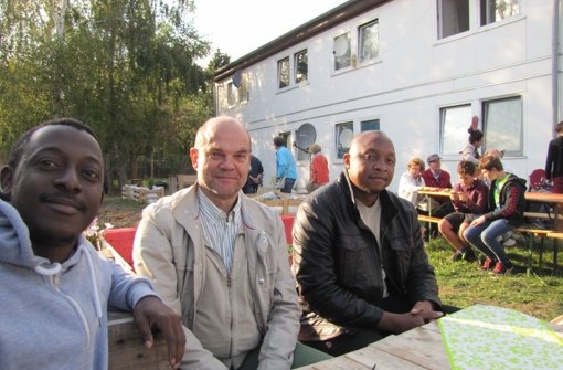 Der Nachbar Karsten Hoffmann (Mitte) unterhält sich mit den Flüchtlingen Silas Dingoke (l.) und Marko Kengne (r.) aus Kamerun über deren Zukunft in Deutschland. Foto: Julia Schuster