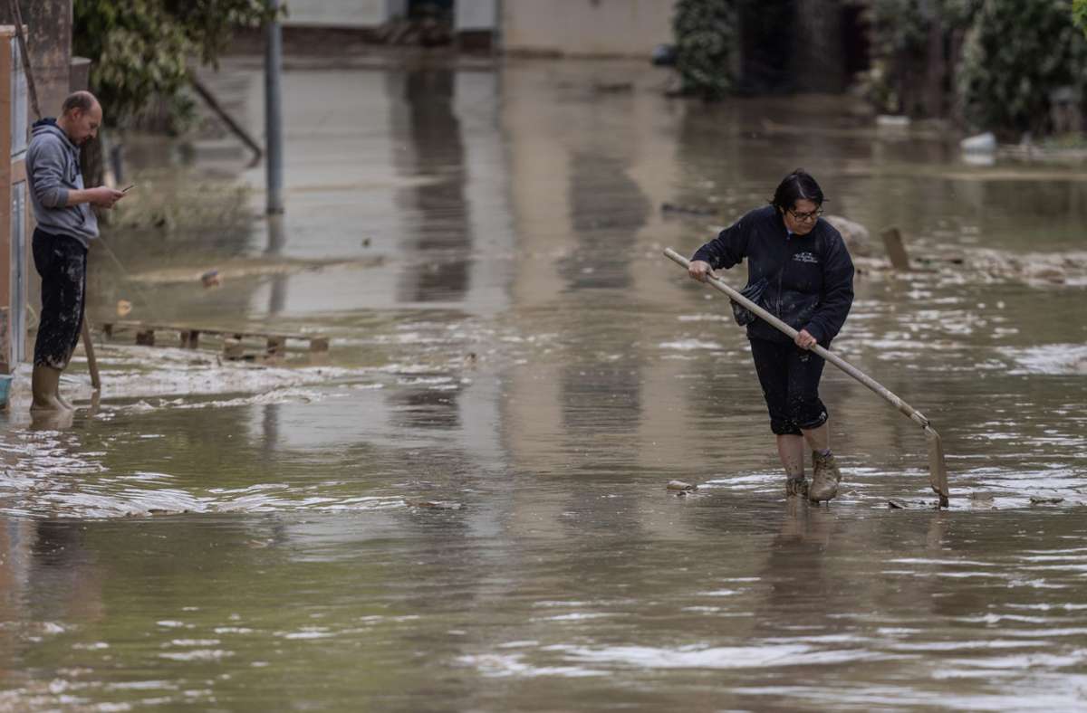 . . . . Anwohner versuchen nach Überschwemmungen eine Straße von Schlamm und Wasser zu befreien.