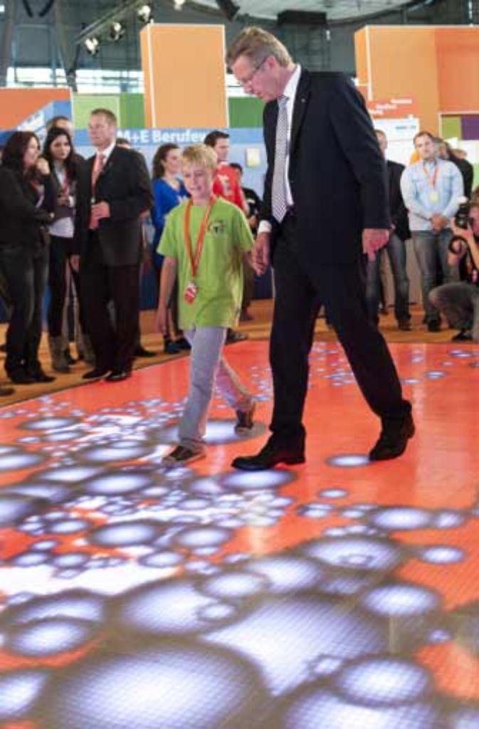 Der gemeinsame Weg in die Zukunft? Bundespräsident Wulff geht bei der Eröffnung der Messe Ideenexpo 2011 mit einem Jungen über einen sogenannten motion floor. Dieser reagiert auf Schritt und Tritt mit spektakulären Lichtbildern und Effekten – mit einem optischen Feuerwerk unter den Füßen.