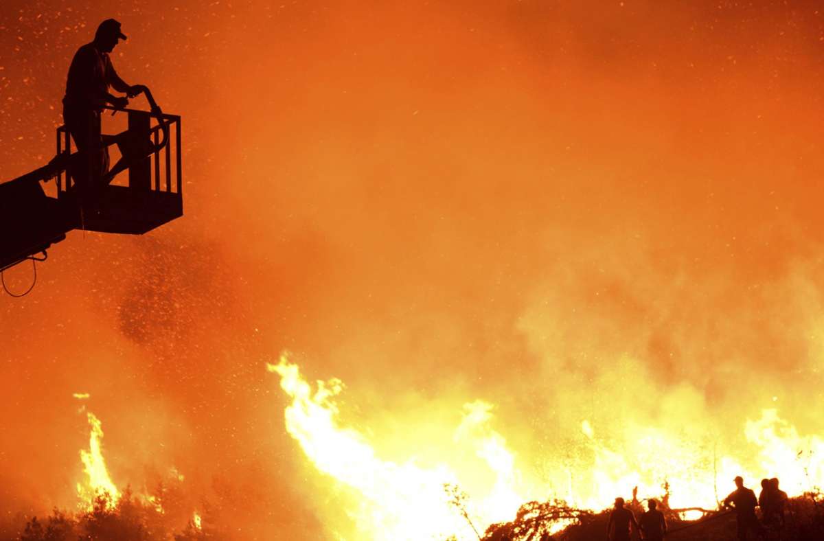 Ein Feuerwehrmann richtet Hochdruckwasser aus einem Schlauch auf die sich ausbreitenden Flammen in den Ausläufern des Pentadaktylos-Gebirges im Norden Zyperns.