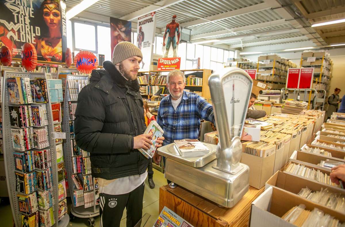 Inhaber Frieder Maier lässt einen Kunden seine Comics wiegen.