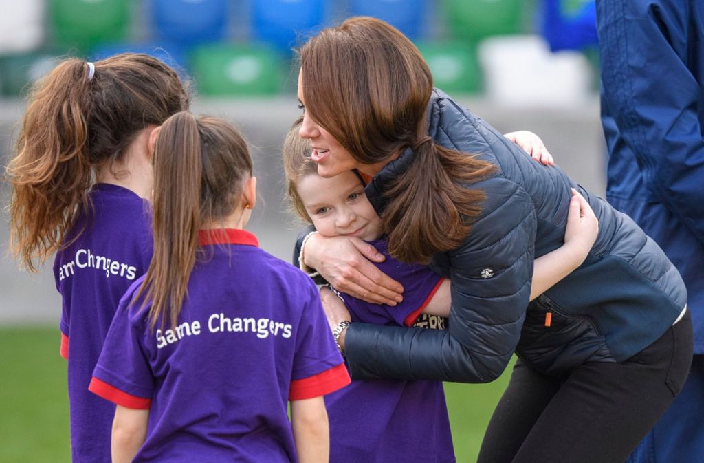 Bilder, die die Royals gerne von sich sehen: Herzogin Catherine knuddelt Kinder in Nordirland während eines Fußballspiels. Tim Rooke hat die Szene fotografiert.