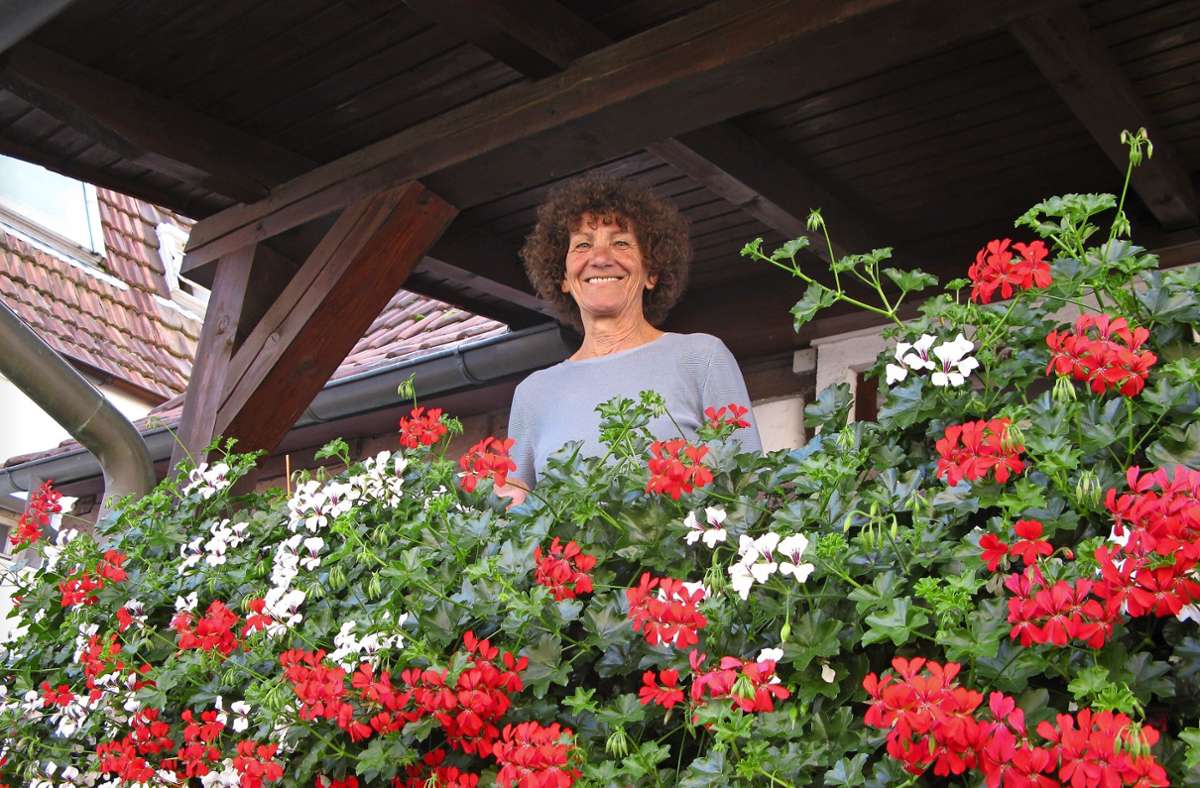 Gudrun Riedele auf ihrem Balkon umgeben von  den rot-weißen Geranien, die das Fachwerkhaus in Fellbach schmücken. Foto: /Eva Schäfer