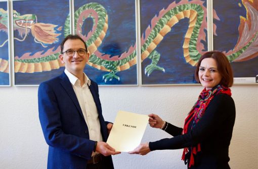Tim Praßel erhält von Melanie Stumpf vom Regierungspräsidium die Bestellungsurkunde als Rektor. Foto: Zeppelin-Gymnasium Stuttgart