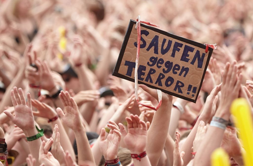 Rockfans halten vor der Hauptbühne beim Auftritt der Band „Sum 41“ Schilder gegen den Terror hoch.