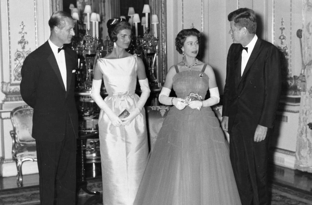 1961 empfingen Elizabeth II. und Prinz Philip den US-Präsidenten John F. Kenney und dessen Frau Jacky. Man kann es auf diesem Bild leider nicht sehen: Beide Damen trugen Blau – aber da enden die Gemeinsamkeiten. Die First Lady verströmte in ihrem Kleid mit U-Boot-Ausschnitt den Aufbruch in die noch jungen „Swinging Sixties“, die Queen hielt sich mit einer klassischen Tüllrobe eher an modische Traditionen.