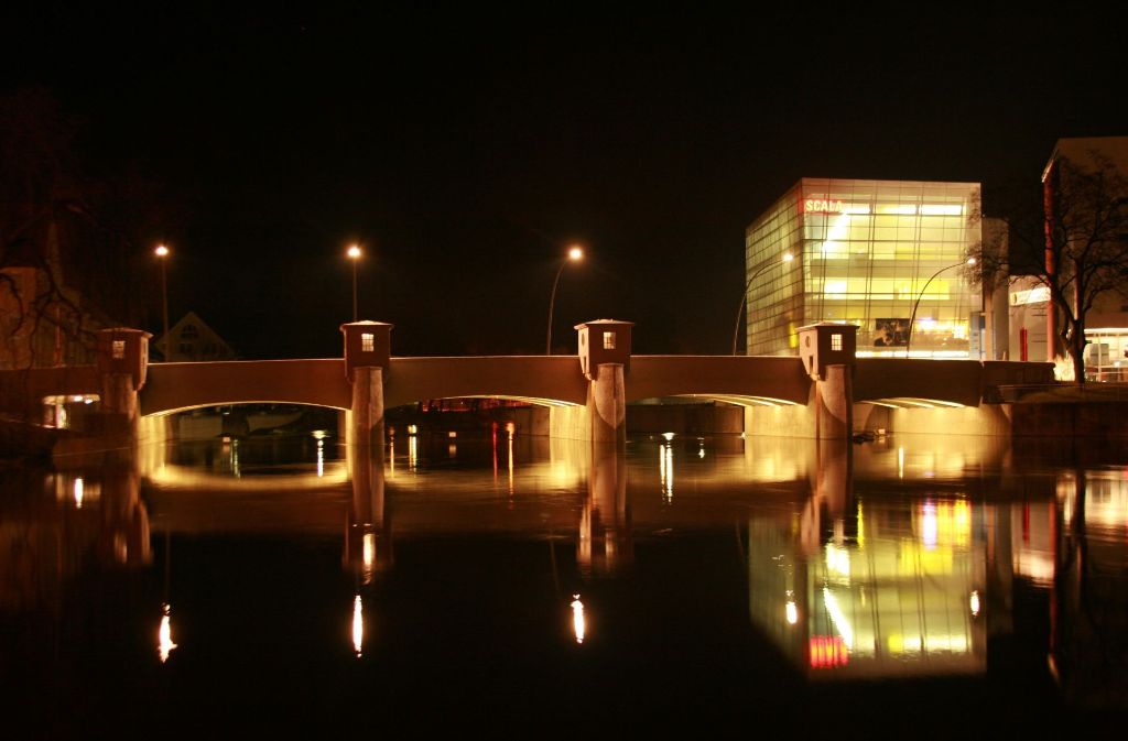 Das Scala-Wehr und das gleichnamige Filmtheater (rechts) bei Nacht.