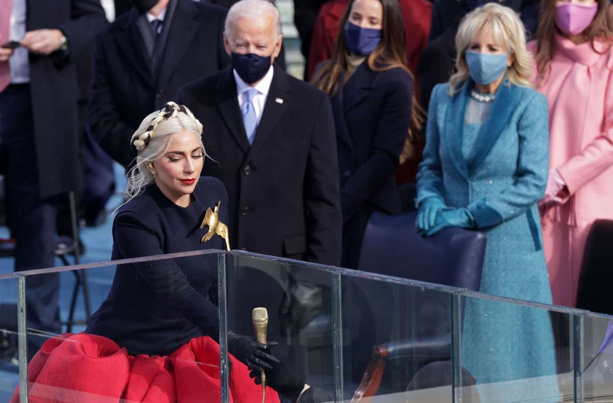 Lady Gaga geht zum Mikrofon, hinter ihr Joe und Jill Biden